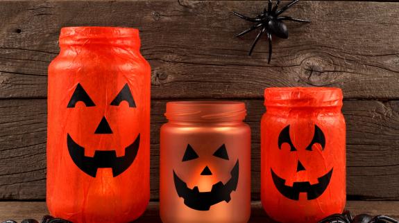 Mason jar Halloween Jack o Lanterns against an old wood background.