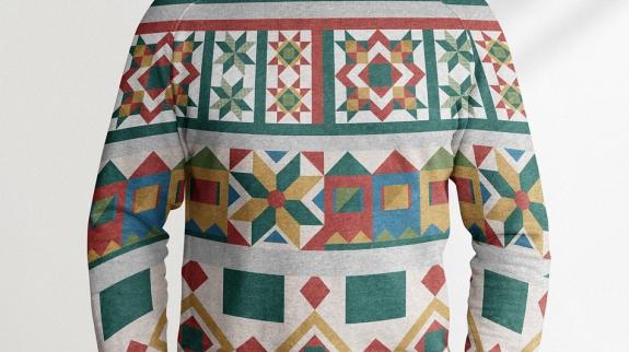 A person is wearing a Christmas sweater indoors. The sweater features distinct patterns and has long sleeves.