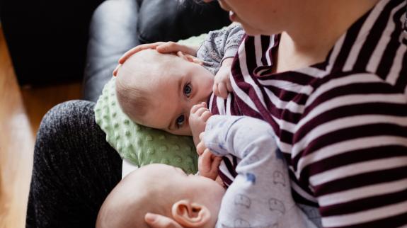 Woman nursing twins on her lap.
