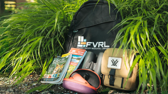 A travel backpack featuring, binoculars, and a map, perfect for exploring nature.