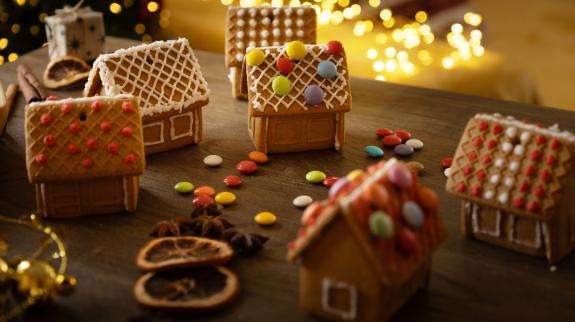 Multiple mini decorated gingerbread houses standing on the table in a cozy Christmas atmosphere.