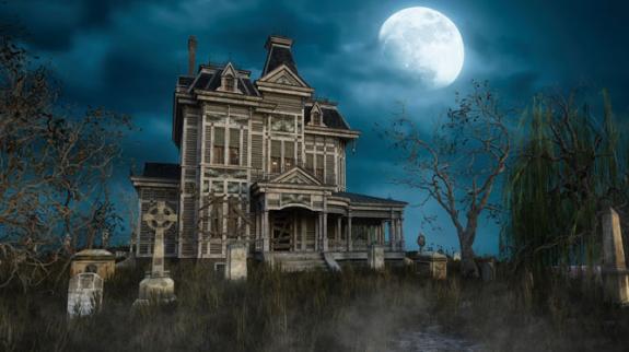 An old abandoned Victorian mansion house with tomb stones in the garden under a moonlit sky.