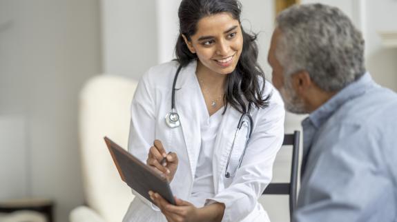 A young female South Asian doctor discusses medical results with a senior South Asian man.