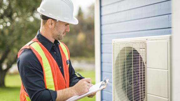 A technician working on heat pump outdoor unit.