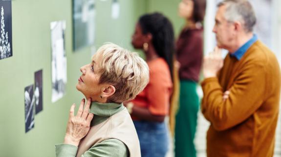 Selective focus shot of senior and young people visiting black and white photography exhibition in modern art gallery.