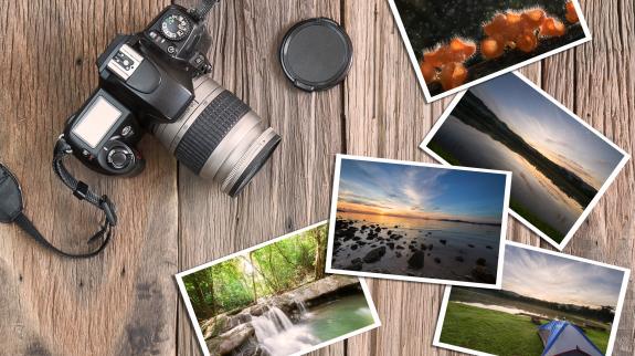 Old grunge camera and photos on vintage grunge wooden background in vintage style.