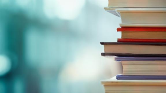 Book stack in the library room and blurred bookshelf.
