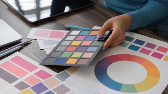 A designer evaluates a color palette, reviewing swatches and color wheels to finalize design choices, showcasing creativity and attention to detail.
