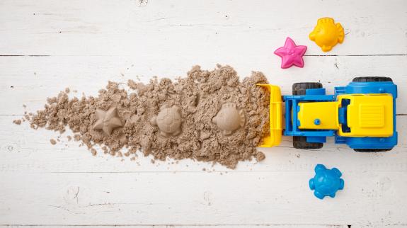 A tractor rakes kinetic sand along with plastic sea animal molds.