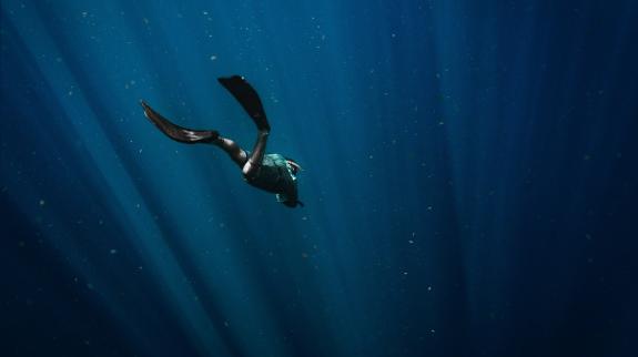 Diver swimming deeper into the ocean.