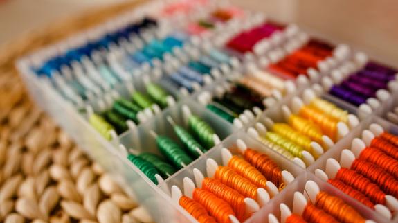 Various colours of embroidery floss sorted in a container. 