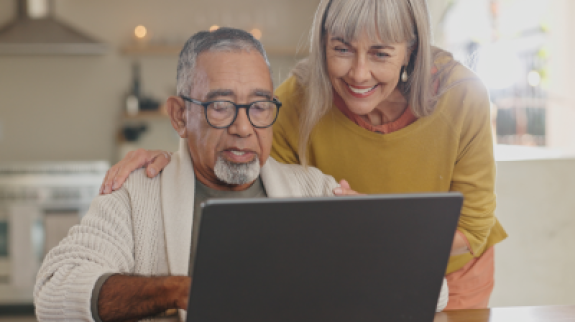 A man and woman looking at a laptop screen.