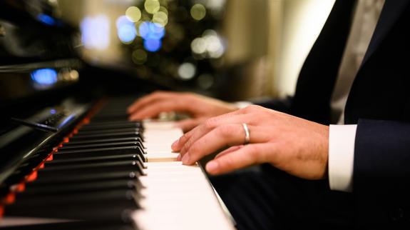 Close-up of a musician's hands playing a digital piano during a Christmas party, creating a festive and musical atmosphere.