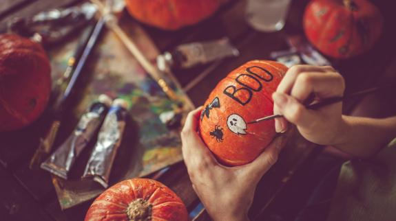Woman painting on pumpkin for Halloween.