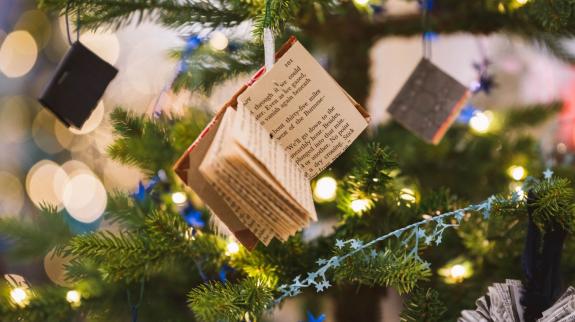 a small open book hangs on a tree that is decorated with lights
