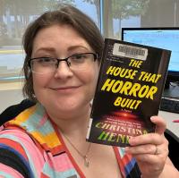 Reading Adviser Sally poses with a book titled "The House That Horror Built."