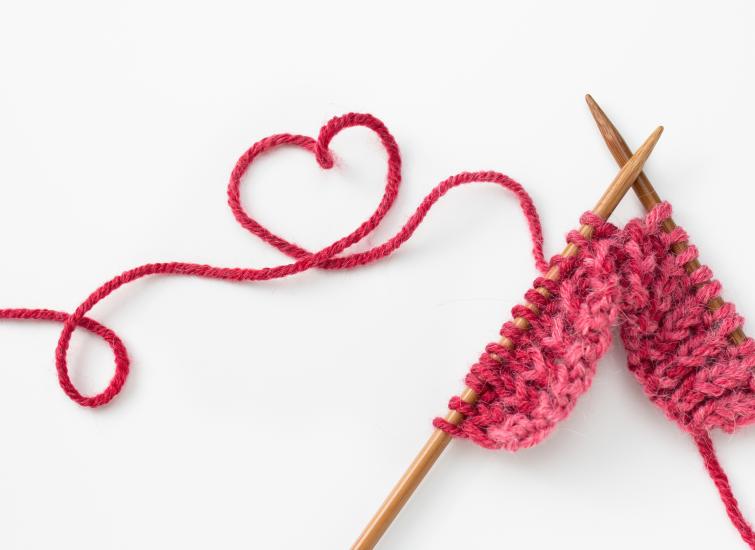 Incomplete heart knitting project with wooden needles