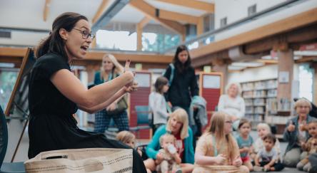  A librarian seated, surrounded by children, creating a lively and engaging story time atmosphere.