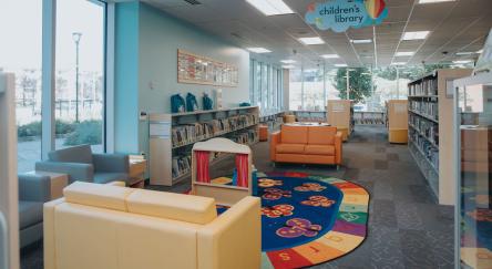 A vibrant library filled with colorful furniture and shelves brimming with books, inviting readers to explore.