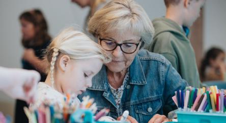 An older woman and a young girl happily crafting together, sharing creativity and joy in their artistic project.
