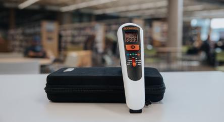 A thermal leak detector placed on a table in a library, showcasing its use for measuring surface temperatures.