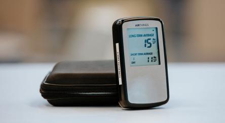 A radon detector resting on a black case, highlighting its compact size and practical use.