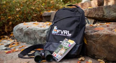 A travel backpack featuring, binoculars, and a map, perfect for exploring nature.