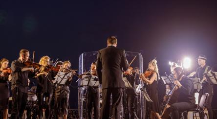 Musicians playing on stage at night, illuminated by stage lights, showcasing their talent in a lively music setting.