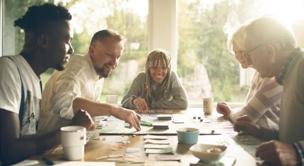 A diverse group of friends gathered around a table, enjoying a lively board game night together.