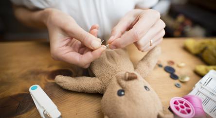 A person is engaged in sewing a teddy bear, skillfully fixing the soft toy with love and attention to detail.