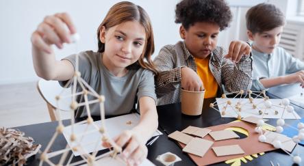 Diverse group of children making wooden models during art and craft class at the library.