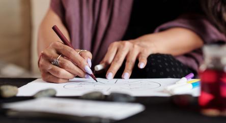 Close up of woman's hands, with purple painted fingernails, as she practices line drawing