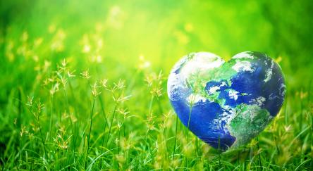 Earth in heart shape on green grass on sunlight - Earth Day concept. Elements of this image furnished by NASA.