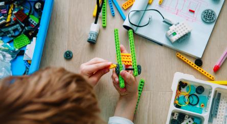 A child building a robot our of connecting blocks at robotic technology library program.