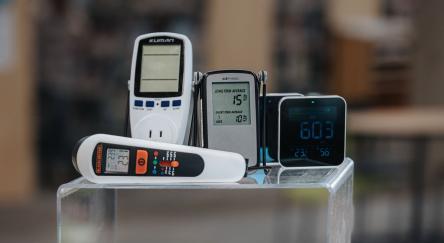 Various Playground items, including Air Quality Monitor, Radon Detector, and Thermal Leak Detector are artfully displayed on top of a library bookshelf.