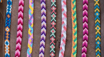 Colourful embroidery floss bracelets on brown table.