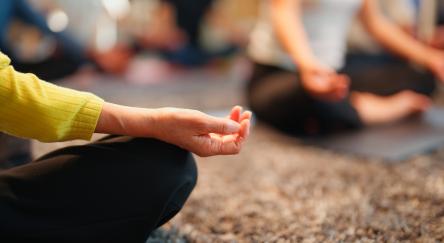 A woman practicing breathing and meditation, seated with hands raised, reflecting calmness and concentration in a tranquil atmosphere.