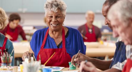 Senior citizens engaged in painting activities at a library program, showcasing creativity and social interaction.