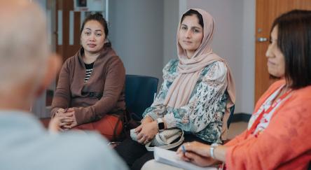 A group of women engaged in conversation while sitting in a circle, fostering a sense of community and connection.