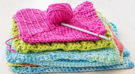 Crocheted dishcloths, with a hook and a ball of yarn.