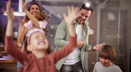 Parents and their young children dancing around with bubbles.