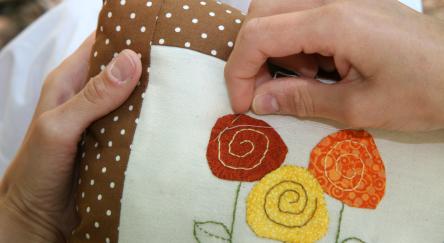 A patchwork cushion with hand stitched applique.