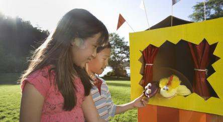 Two friends investigating puppet theater in park.