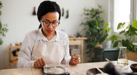 Woman weighing out dry powder on a scale for cooking with in the kitchen.