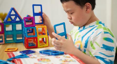 Young boy builds using magnetic Magformer pieces.