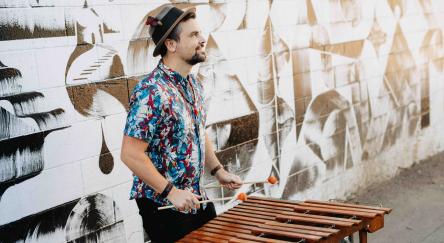 Robin Layne playing the marimba in front of a street mural.