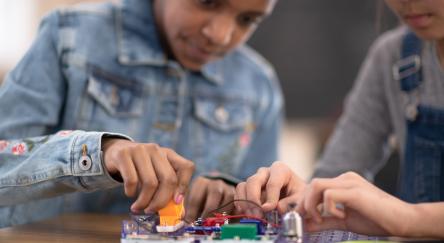 Two tweens work together to learn coding using a Snap Circuit board.