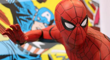 A person dressed as Spider-man in front of a mural of Captain America.