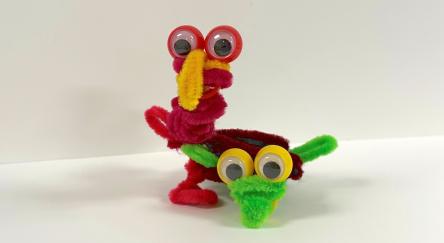 red and green pipe cleaner formed to make a critter with eyes
