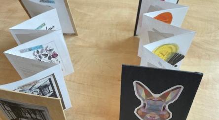 Two hand-made accordion books are displayed on a table.
